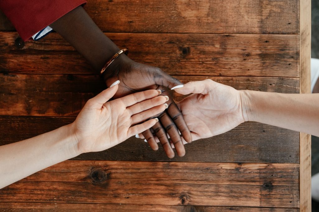 Diverse women stack hands on wooden table